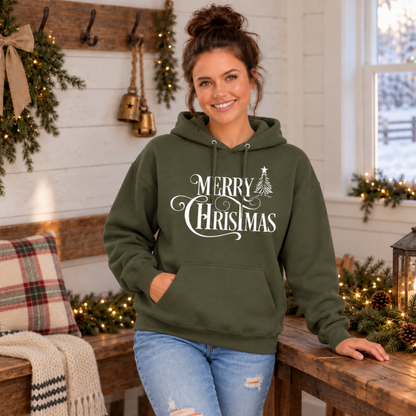 Military green Merry Christmas hoodie with white script and Christmas tree artwork, modeled indoors with Christmas decorations.
