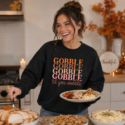 Woman wearing a black “Gobble Gobble Gobble Gobble til you wobble” sweatshirt while serving Thanksgiving dinner in a warm kitchen setting.