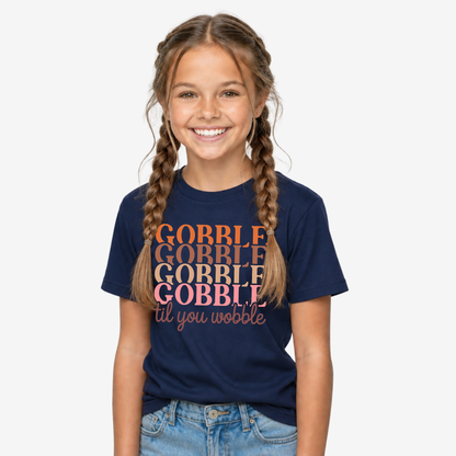 Girl modeling a navy youth T-shirt with the retro Gobble Til You Wobble Thanksgiving design.