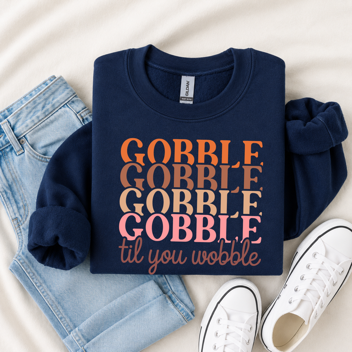 Navy youth sweatshirt flat lay featuring the retro Gobble Til You Wobble Thanksgiving design with jeans and sneakers.