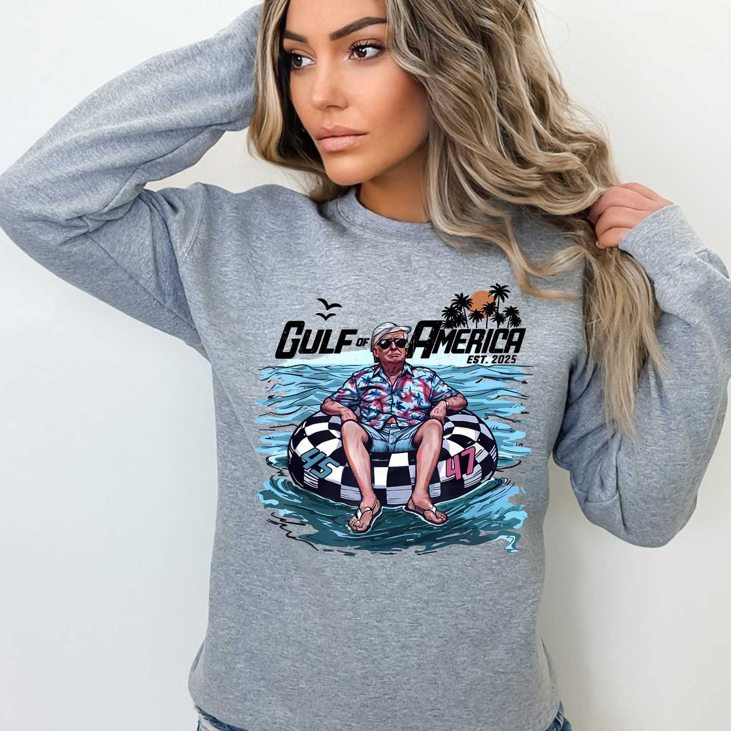 Woman wearing graysweatshirt with retro water float graphic and sunglasses design.