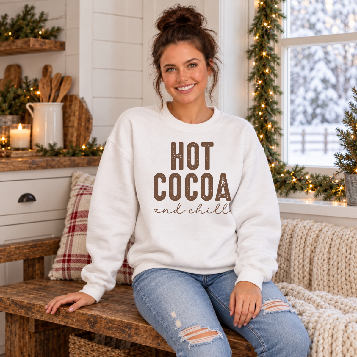 Woman wearing a white Hot Cocoa and Chill sweatshirt in a cozy farmhouse kitchen decorated for Christmas