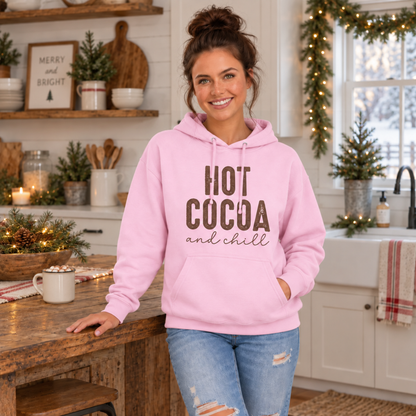 Woman wearing a light pink hoodie with brown Hot Cocoa and Chill design in a festive holiday kitchen