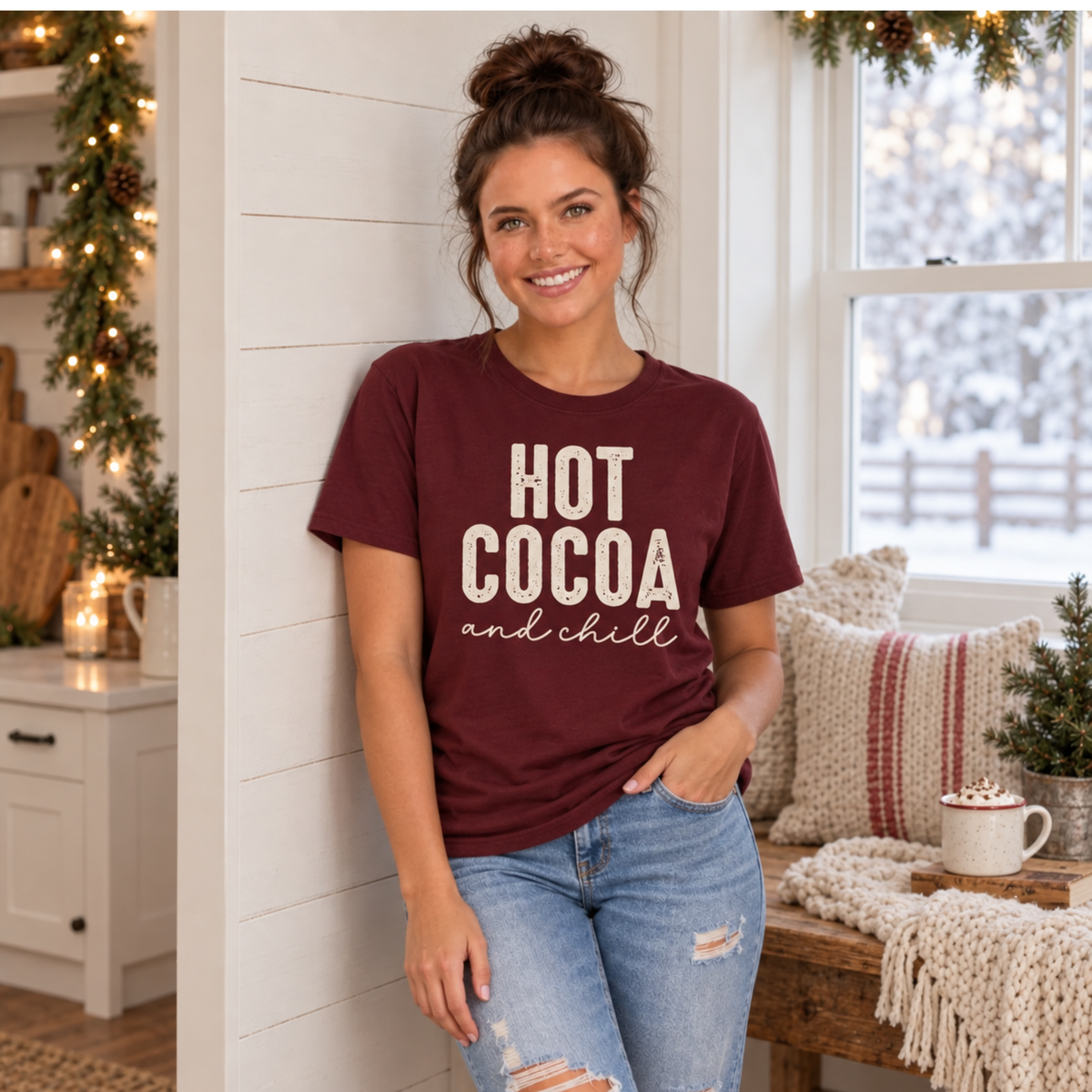 Woman wearing a maroon Hot Cocoa and Chill T-shirt in a cozy holiday kitchen with a cocoa mug
