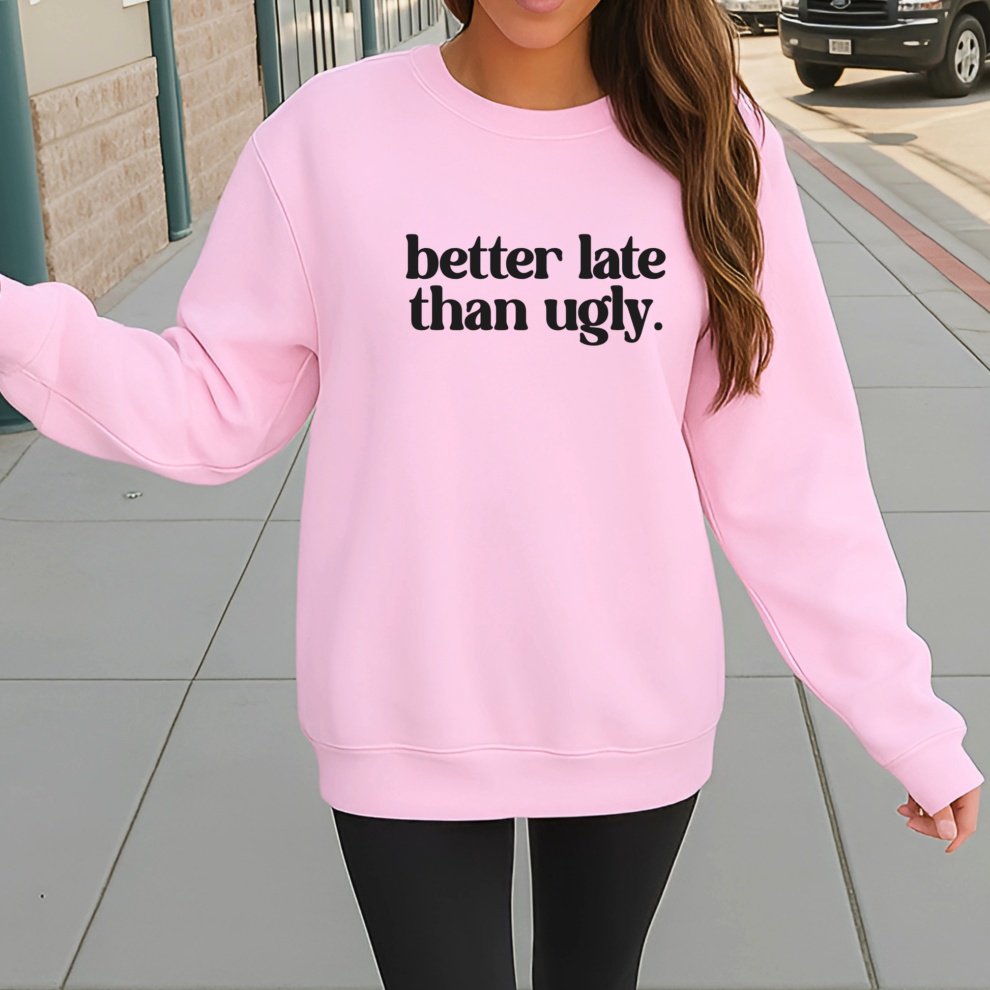Woman wearing light pink “Better Late Than Ugly” sweatshirt styled with distressed denim shorts. Trendy teen and women’s pullover perfect for casual outfits, school, or social media selfies. Unisex fit with cozy comfort and bold attitude.