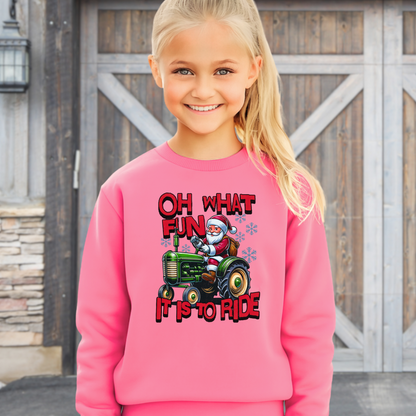 Girl in a pink Christmas sweatshirt with Santa on a green tractor and holiday snowflake accents.
