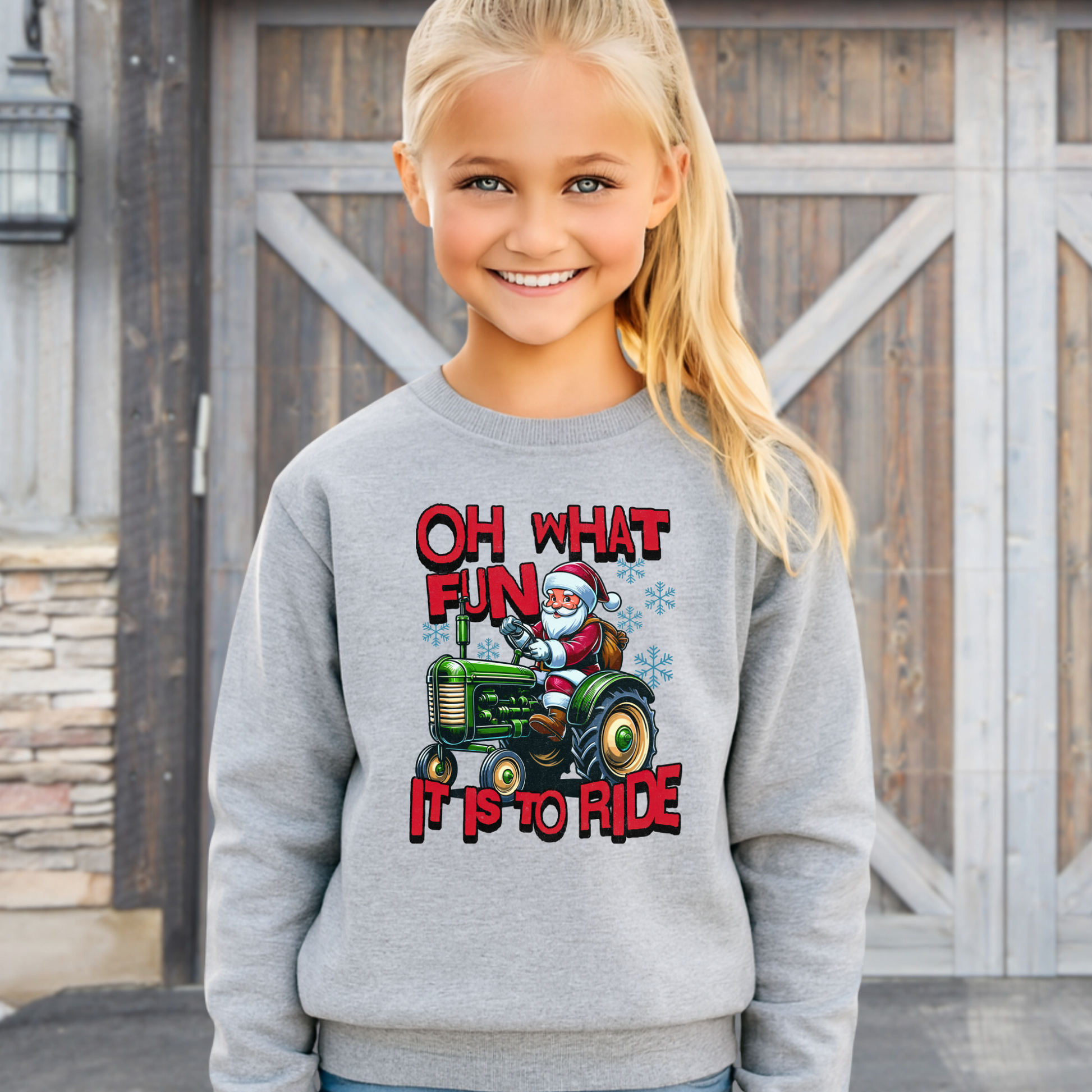 Girl modeling a gray youth Christmas pullover with Santa Claus riding a tractor and bold festive design.
