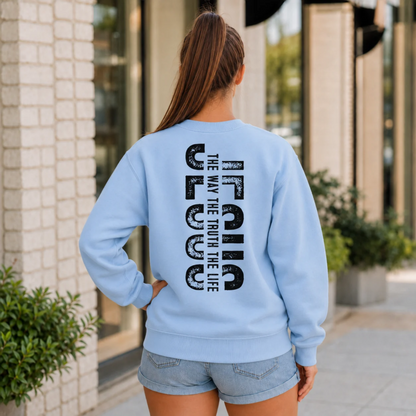 Woman shown from behind wearing a light blue crewneck sweatshirt with vertical black JESUS lettering and “The Way, The Truth, The Life” text.