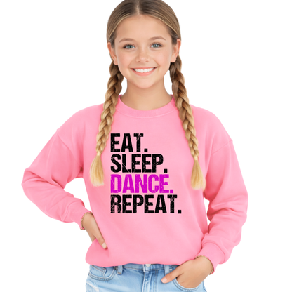 Young girl wearing a pink sweatshirt with 'EAT. SLEEP. DANCE. REPEAT.' text on a white background
