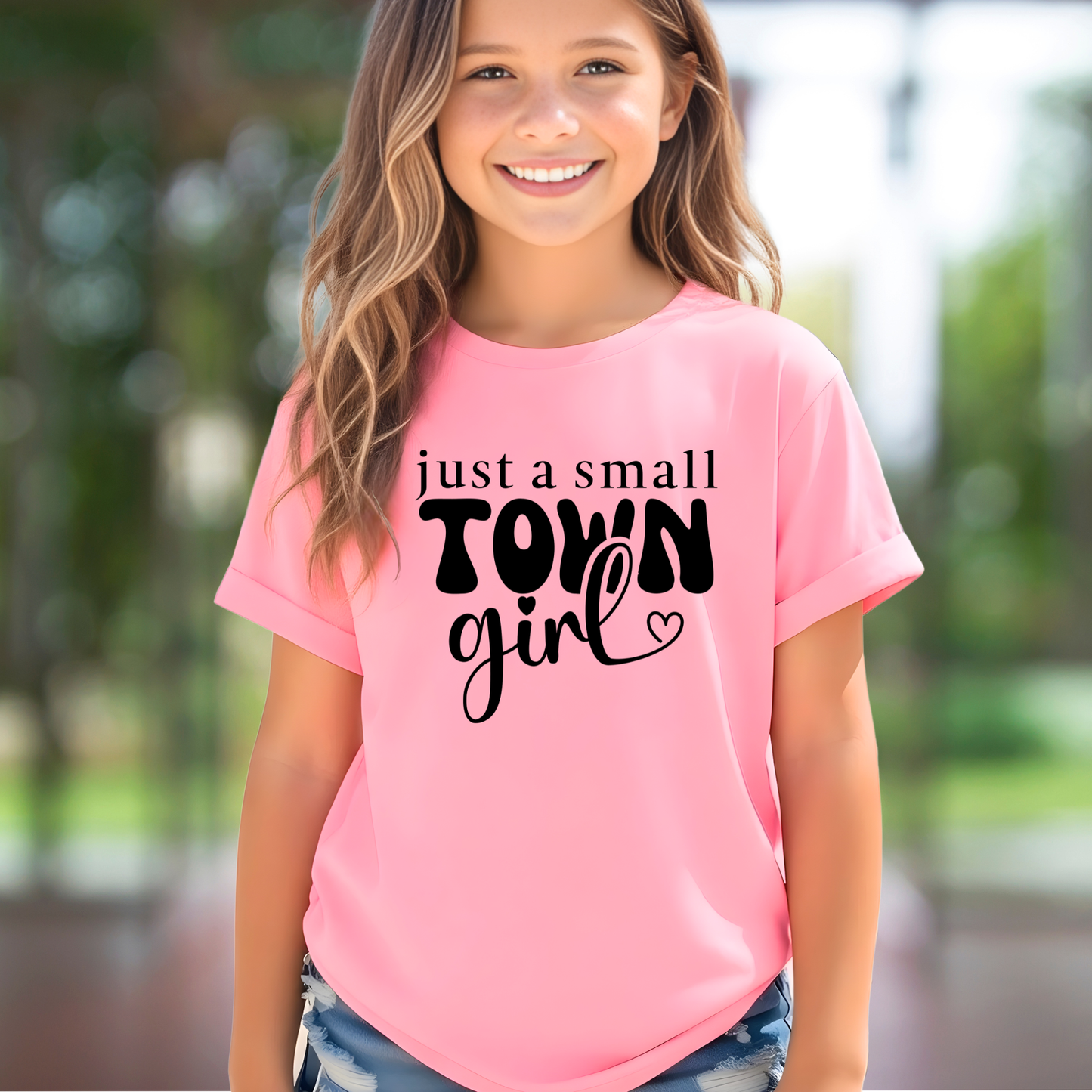 Youth girl wearing pink t-shirt with “just a small town girl” graphic design, cute trendy kids shirt, casual outfit