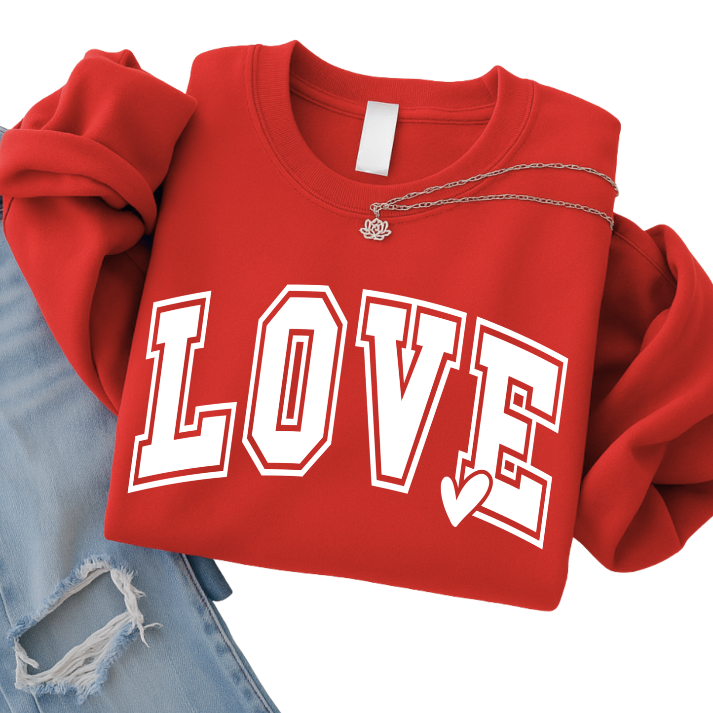 Red LOVE graphic sweatshirt folded flat lay with bold white varsity lettering and heart detail, styled with denim and necklace, cozy kids Valentine clothing, youth apparel product image