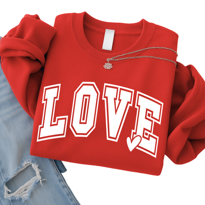 Red LOVE graphic sweatshirt folded flat lay with bold white varsity lettering and heart detail, styled with denim and necklace, cozy kids Valentine clothing, youth apparel product image