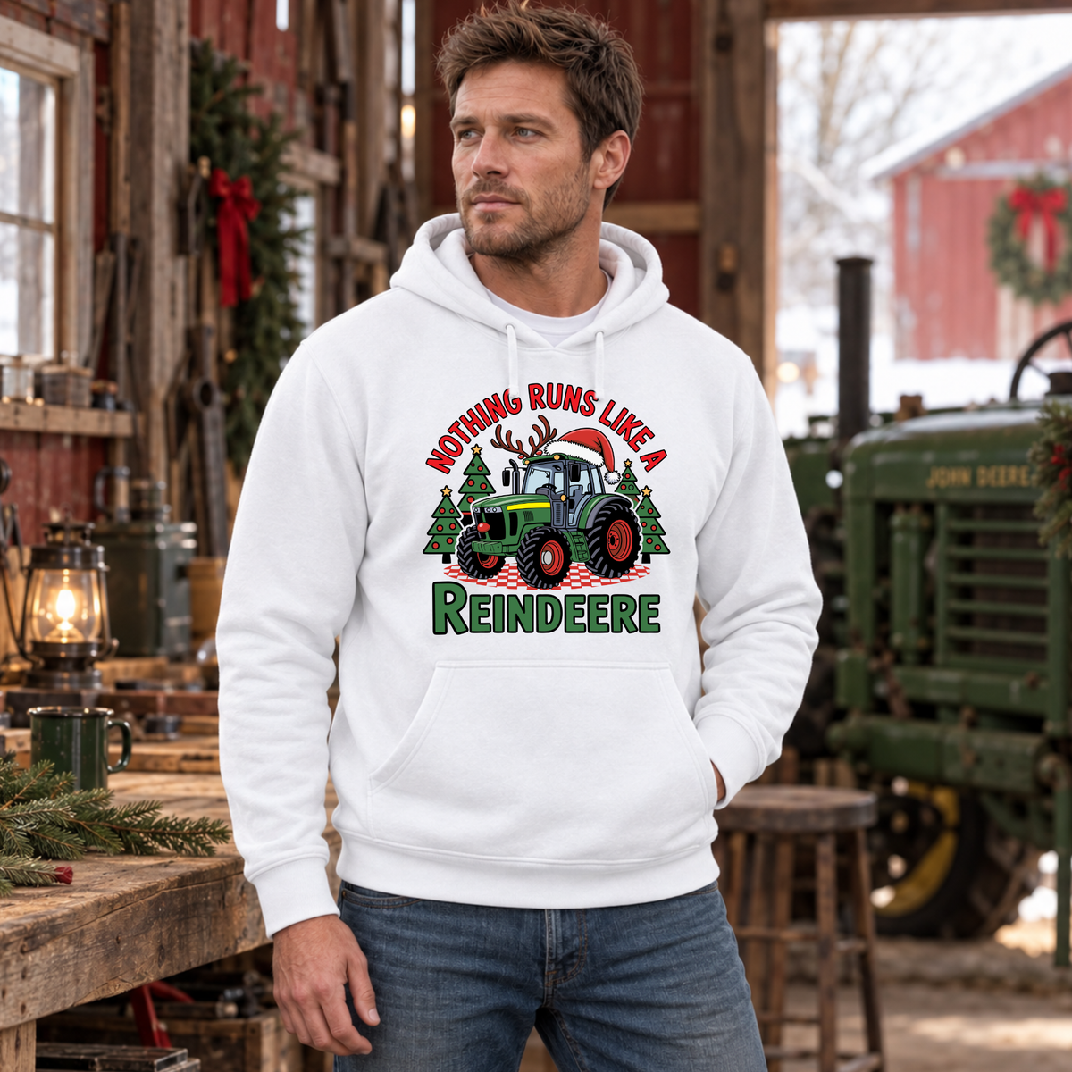 Man in a white Nothing Runs Like a Reindeere hoodie inside a rustic barn beside an old green tractor.