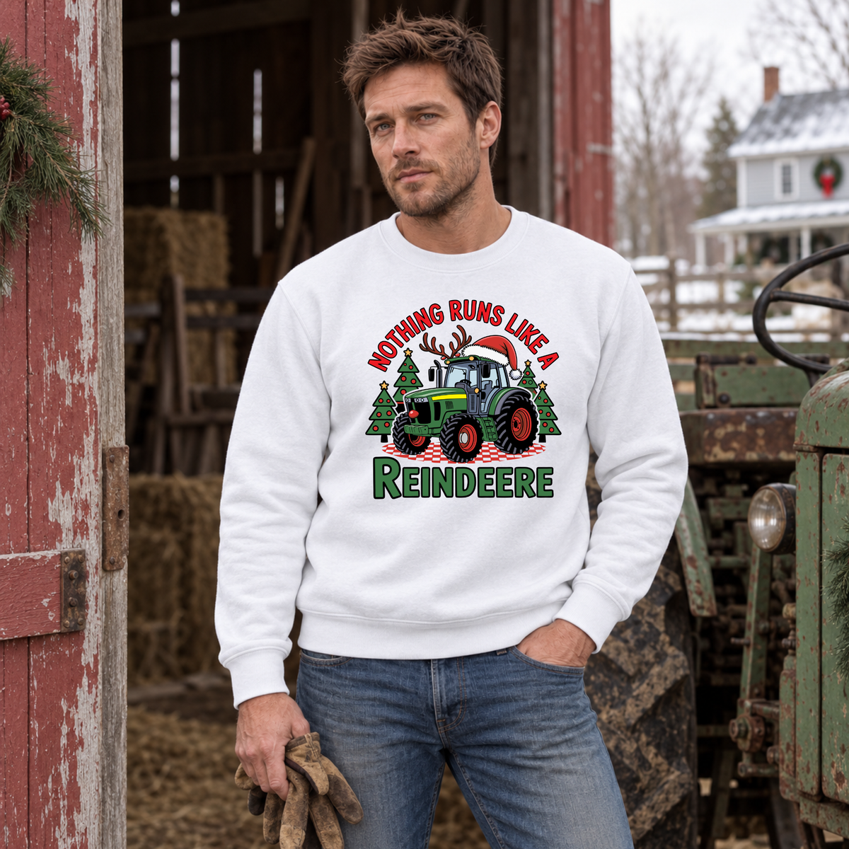 Man in a white Nothing Runs Like a Reindeere sweatshirt beside a red barn and vintage green tractor.