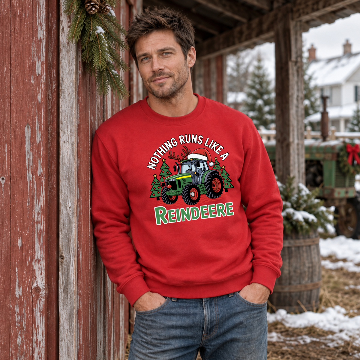 Man in a red Nothing Runs Like a Reindeere sweatshirt leaning against a red barn wall on a snowy farm.