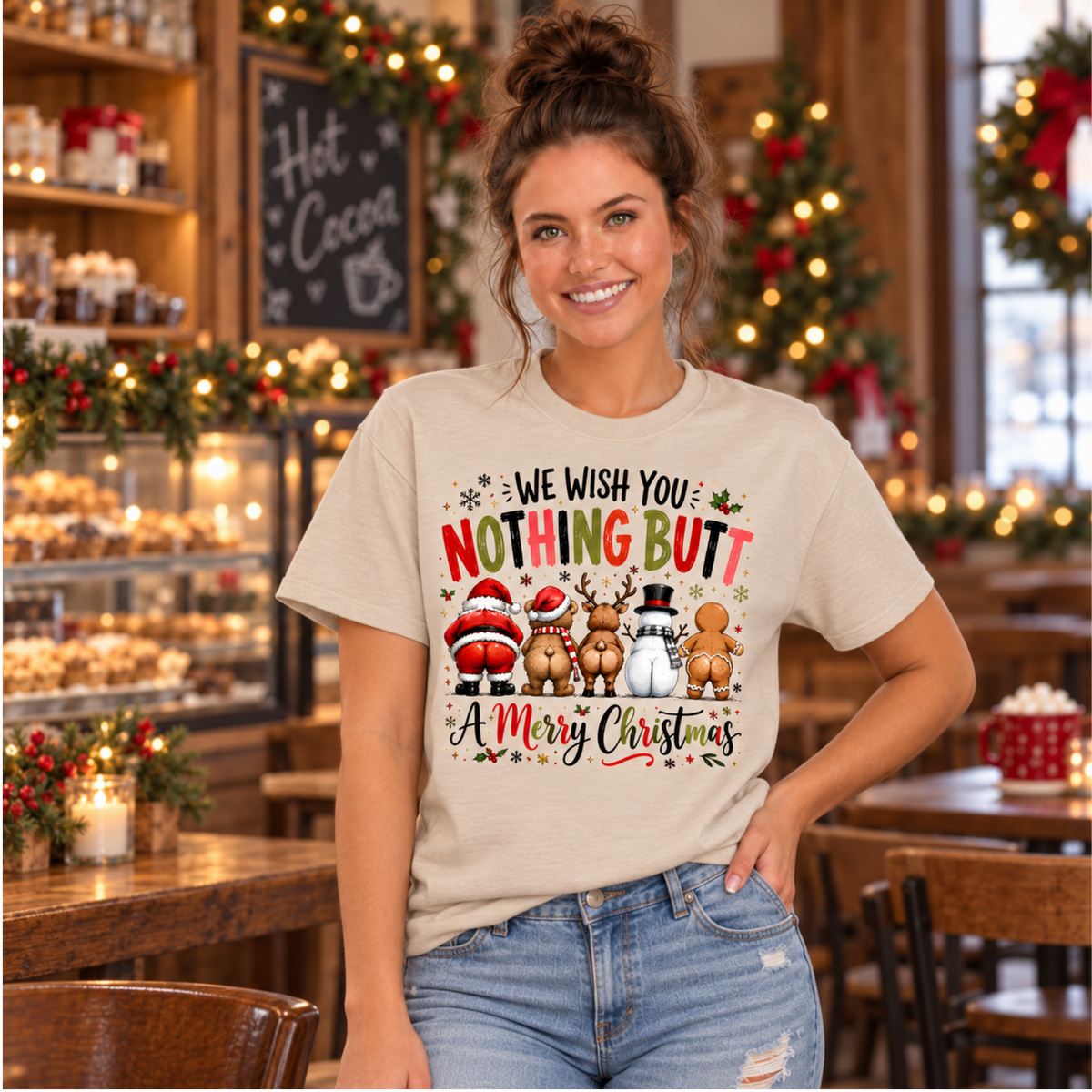 Woman wearing a sand T-shirt with We Wish You Nothing Butt a Merry Christmas design with rear-view Santa, bear, reindeer, snowman and gingerbread characters in a warm Christmas bakery setting