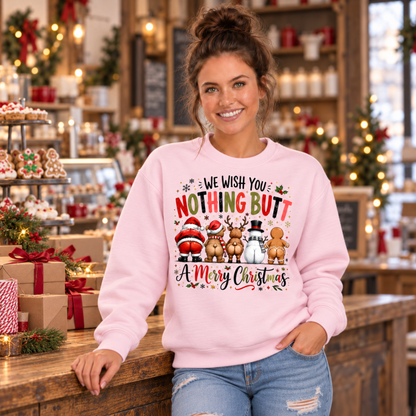Woman wearing a light pink crewneck sweatshirt with We Wish You Nothing Butt a Merry Christmas design with rear-view Santa, bear, reindeer, snowman and gingerbread characters in a decorated holiday bakery