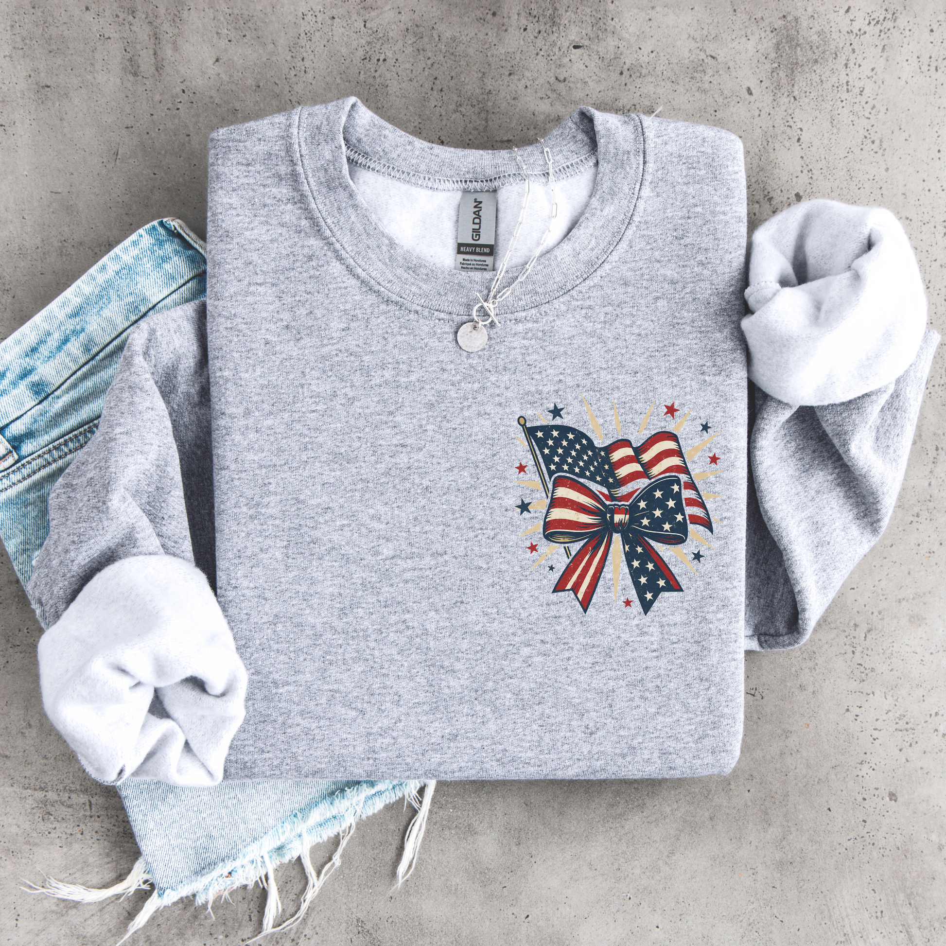 Gray sweatshirt with American flag bow design on a concrete surface