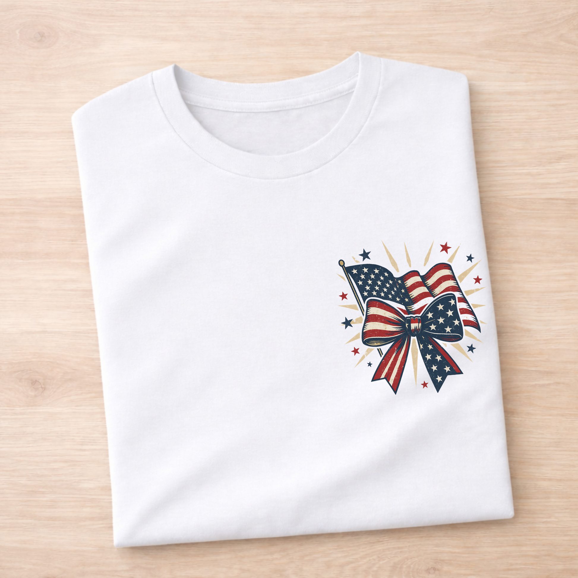 White t-shirt with a patriotic design featuring an American flag and bow on a wooden surface