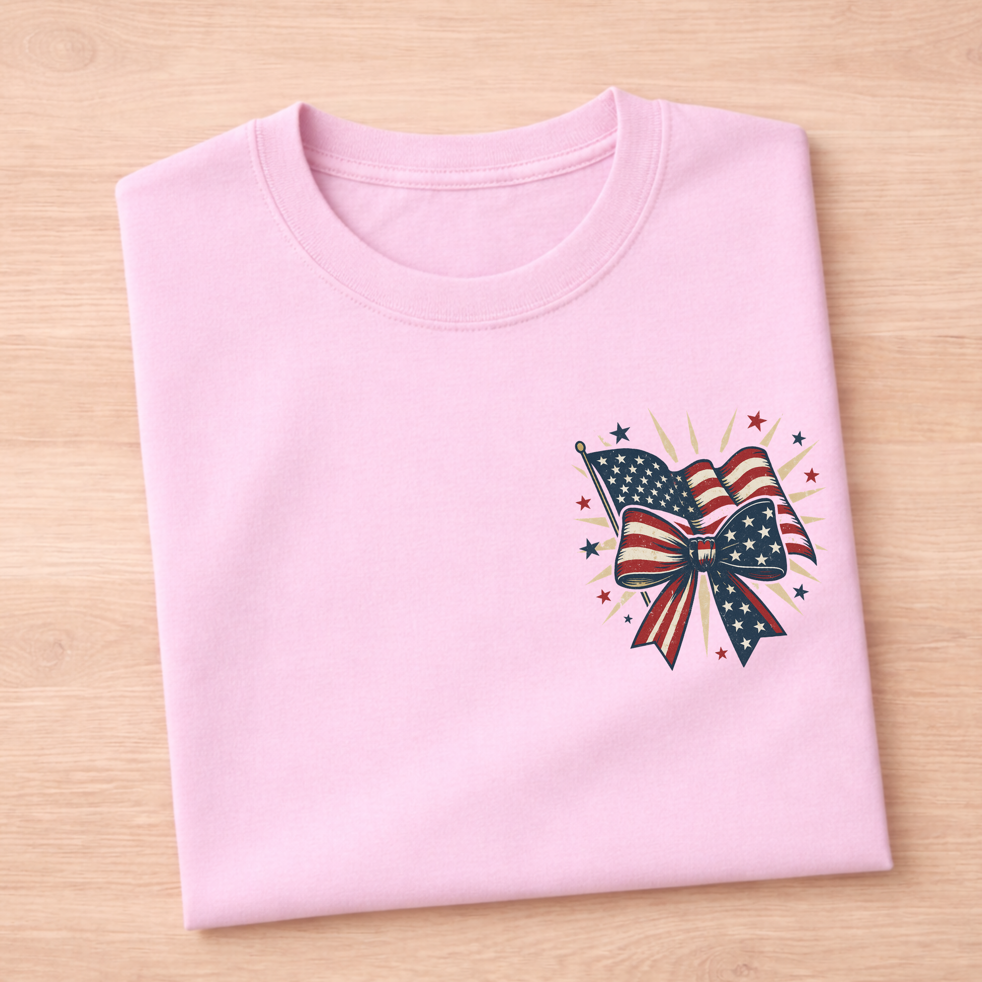 Pink t-shirt with American flag and bow design on a wooden surface