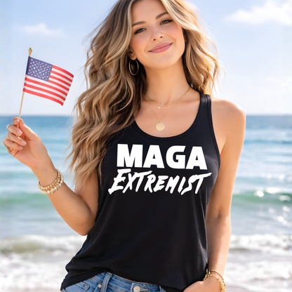 Woman on a beach holding an American flag and wearing a black tank top with 'MAGA Extremist' text.