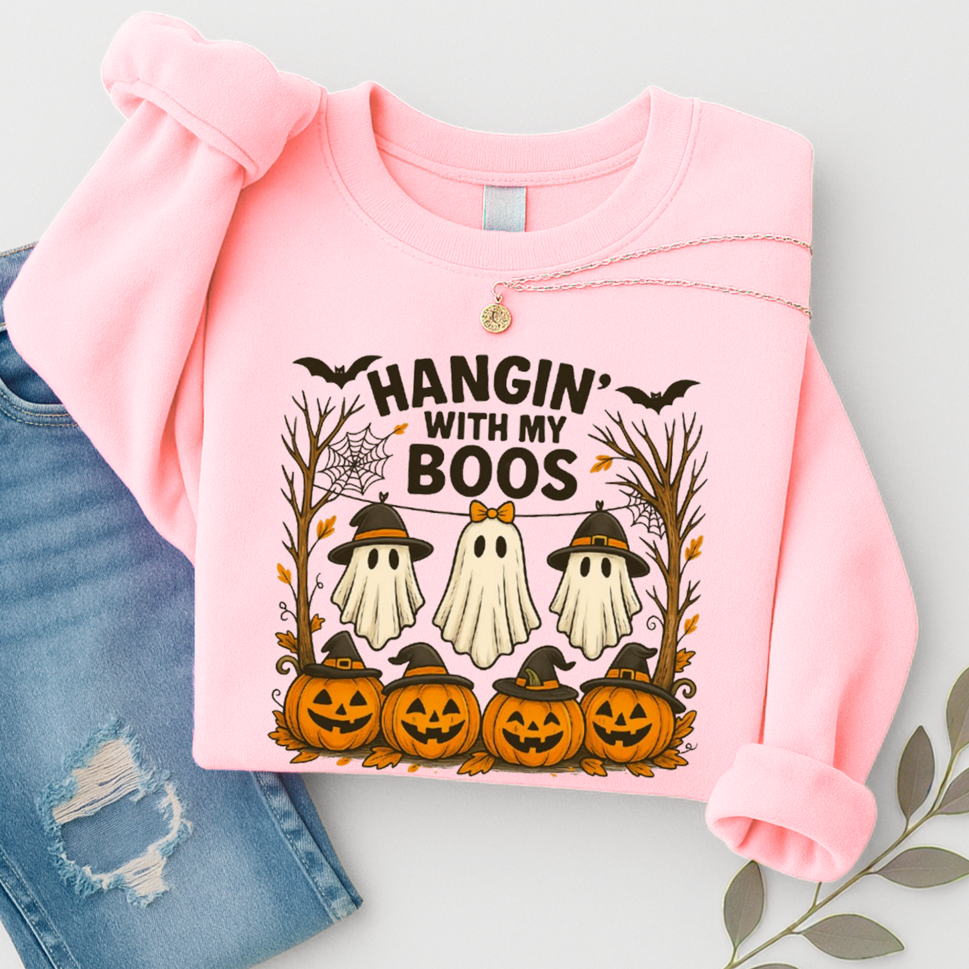 Pink Hangin’ With My Boos sweatshirt featuring a Halloween ghost trio, jack-o’-lantern pumpkins, bats, and fall decor. Unisex crewneck sweatshirt styled with casual jeans.
