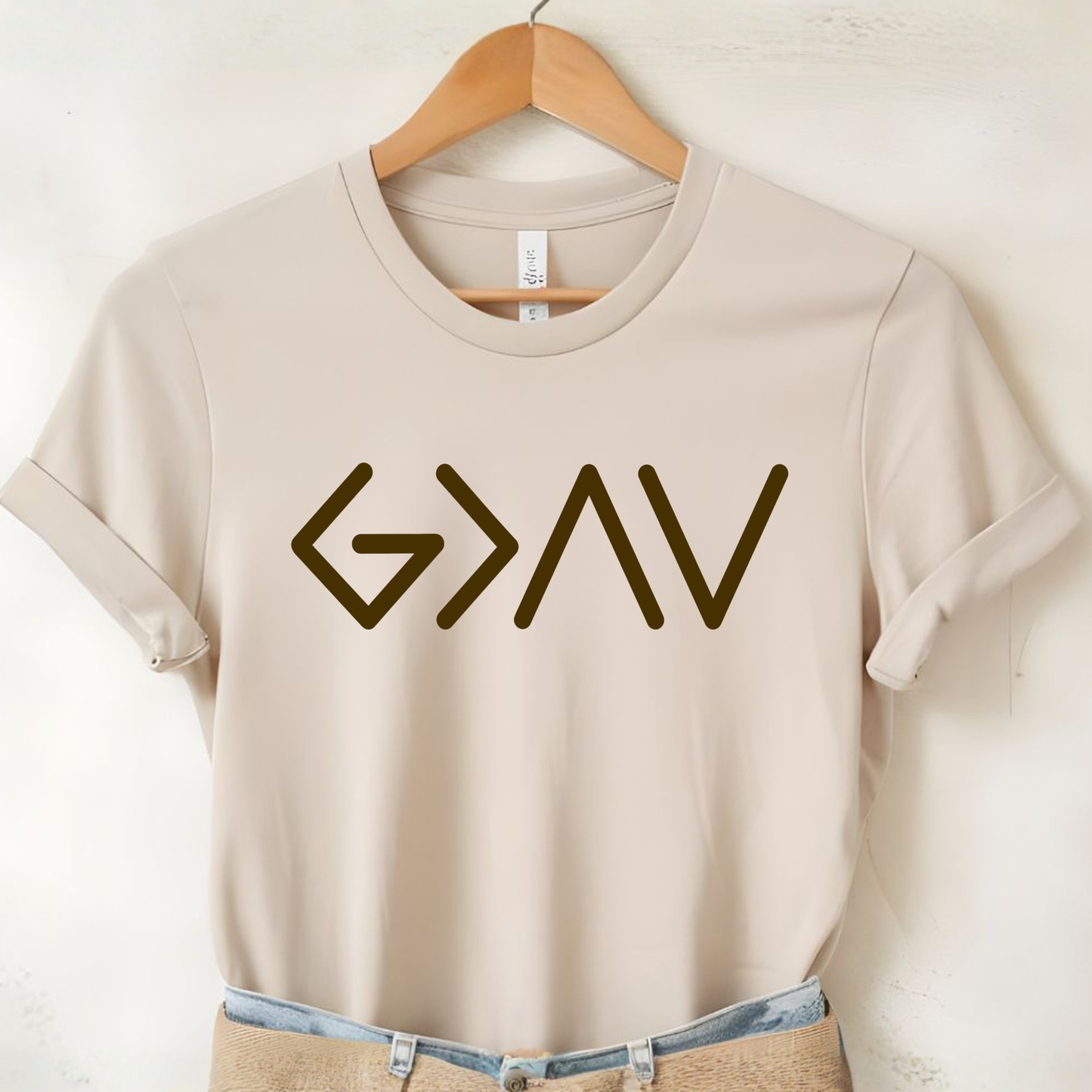 Cream short sleeve t-shirt on hanger with gold God Is Greater Than the Highs and Lows front design