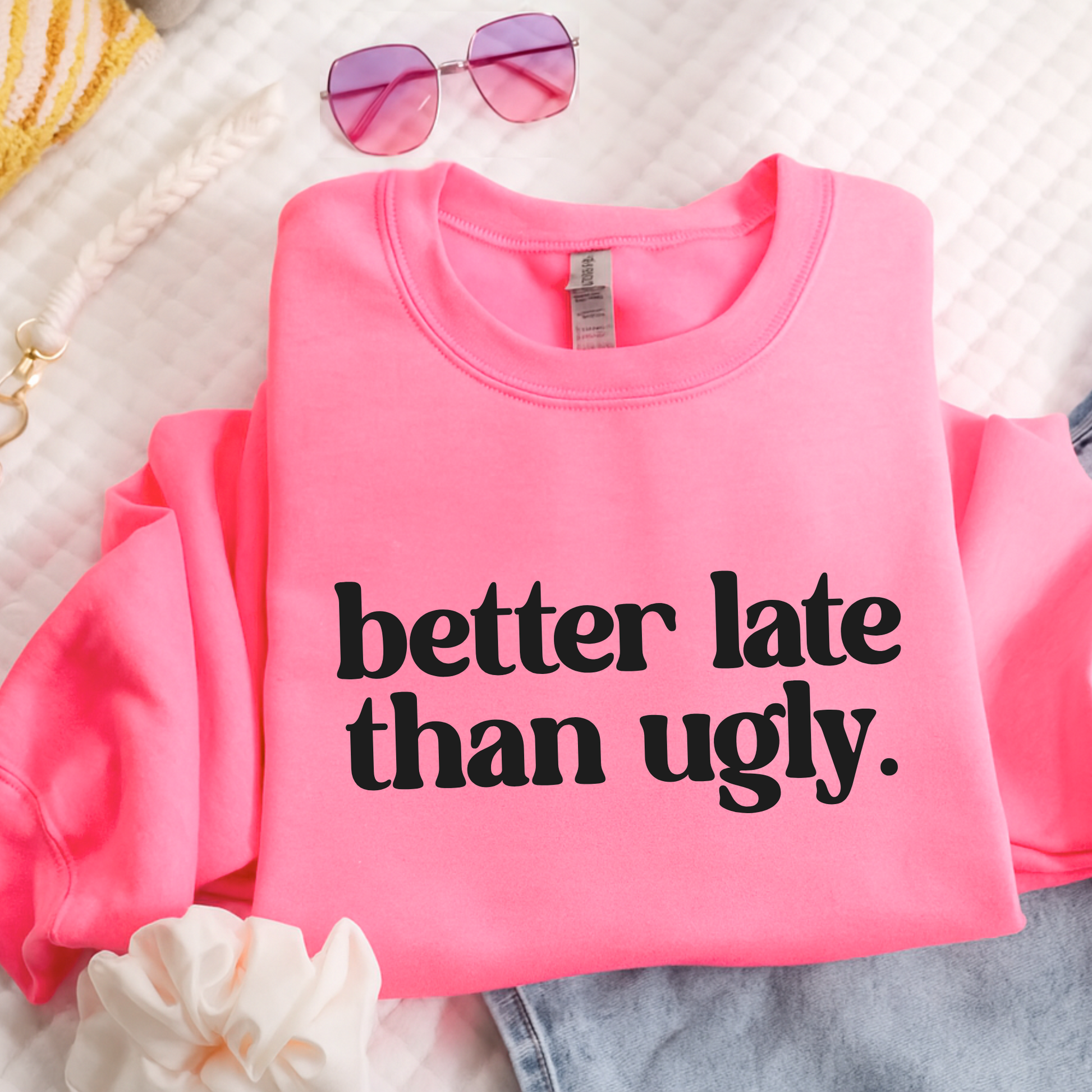 Pink sweatshirt with 'better late than ugly' text on a light background