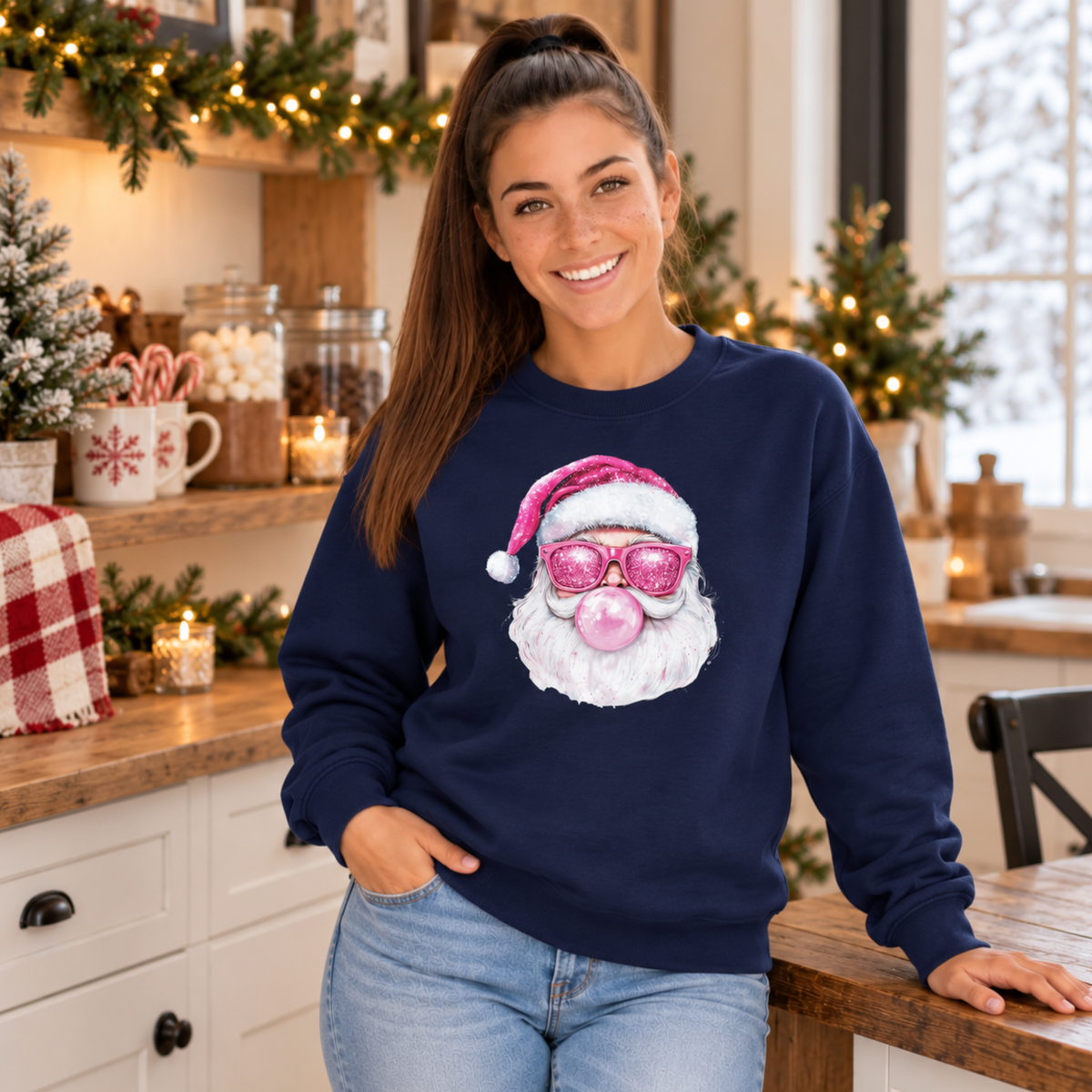 Woman wearing a navy Bubblegum Santa crewneck sweatshirt in a cozy Christmas kitchen with candy canes and greenery