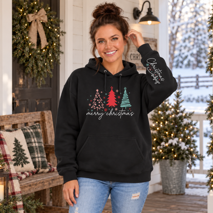 Woman wearing a black Merry Christmas tree hoodie with Christmas Vibes sleeve print on a snowy decorated porch