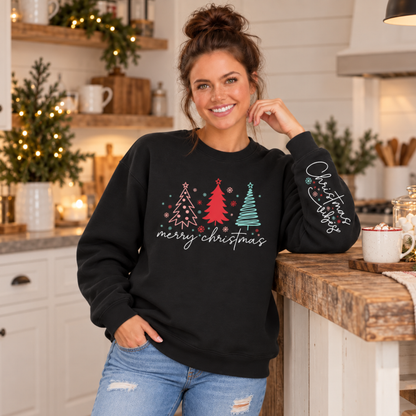Woman wearing a black Merry Christmas tree crewneck sweatshirt with Christmas Vibes sleeve print in a cozy holiday kitchen
