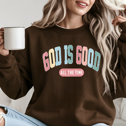 Person wearing a brown sweatshirt with 'GOD IS GOOD ALL THE TIME' text, holding a white mug.