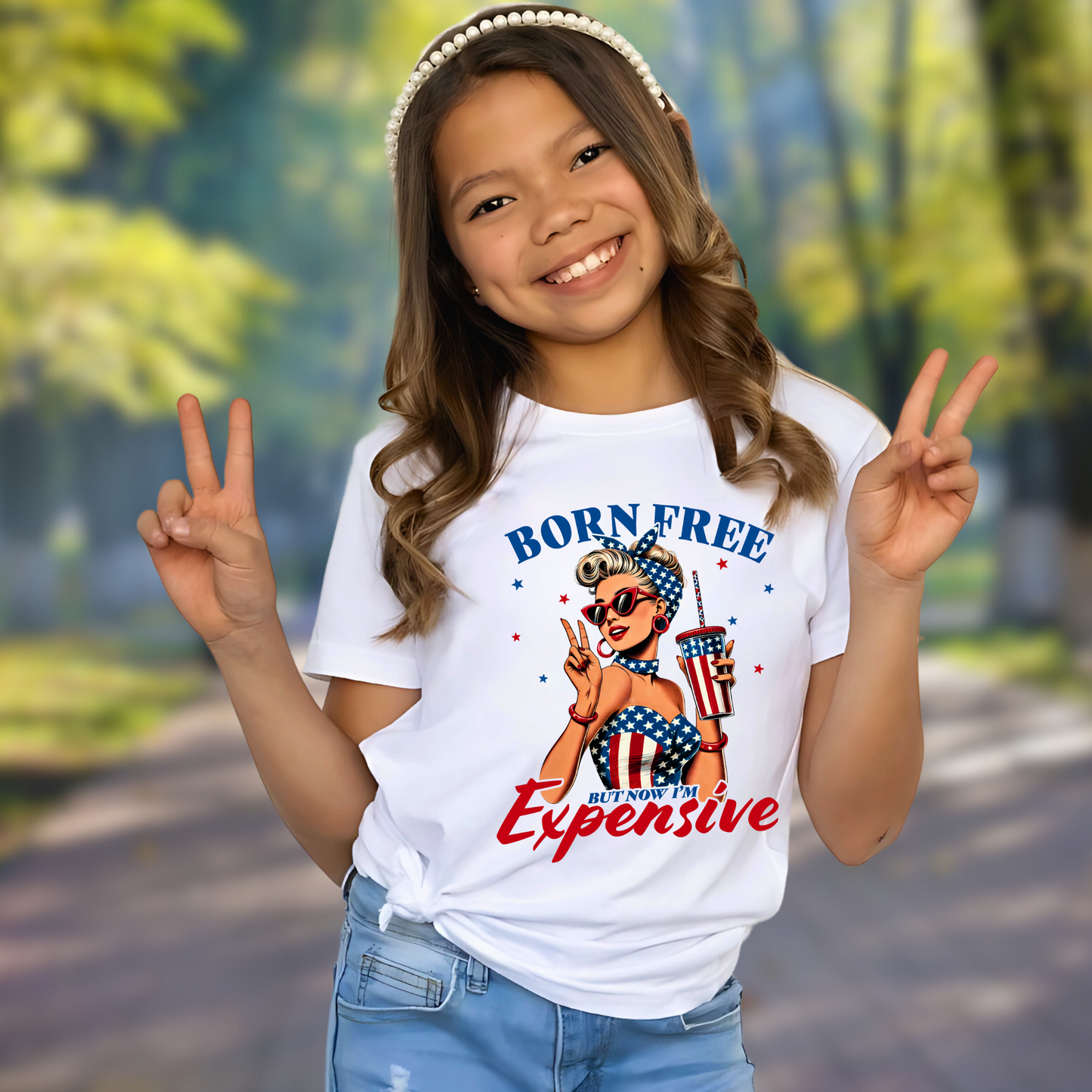 Youth girl wearing white “Born Free But Now I’m Expensive” patriotic T-shirt with American flag drink cup

