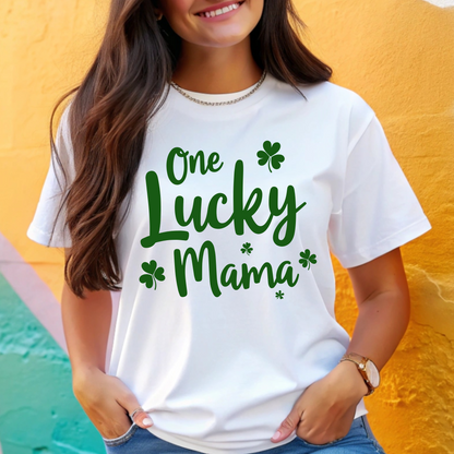 A stylish white t-shirt with "One Lucky Mama" in green script, decorated with shamrocks. Perfect for moms celebrating St. Patrick’s Day in a cute and festive way.