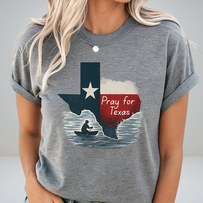 Heather gray unisex Pray for Texas shirt featuring a rustic Texas flag and canoe silhouette. Rolled sleeves and simple accessories create a soft, casual look with Texas support messaging.